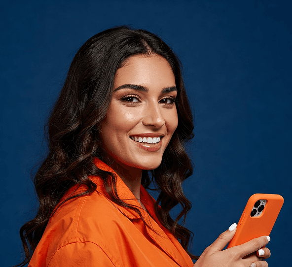 Kobieta w pomarańczowej marynarce patrzy w stronę obiektywu trzymając smartfon